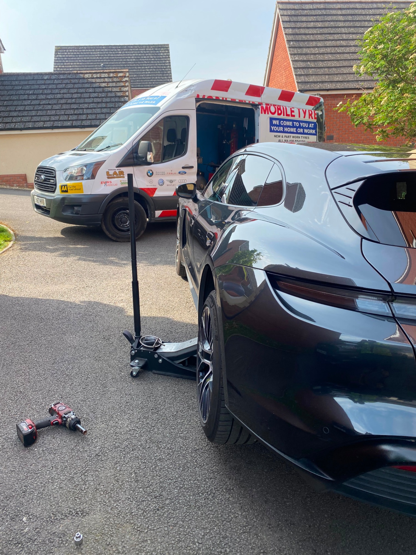Mobile tyre fitting on a Porsche Taycan — trolley jack and impact wrench in position