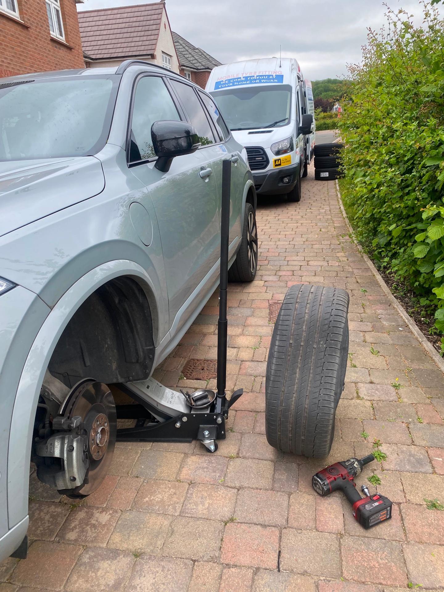 Mobile tyre fitting on an SUV — wheel removed, replacement tyre ready, brake disc visible