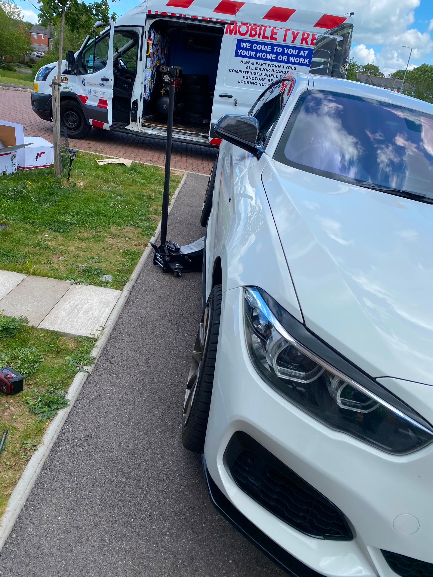 Mobile tyre fitting on a private driveway — BMW jacked up beside the fully stocked Mobile Tyre Fitter 247 van